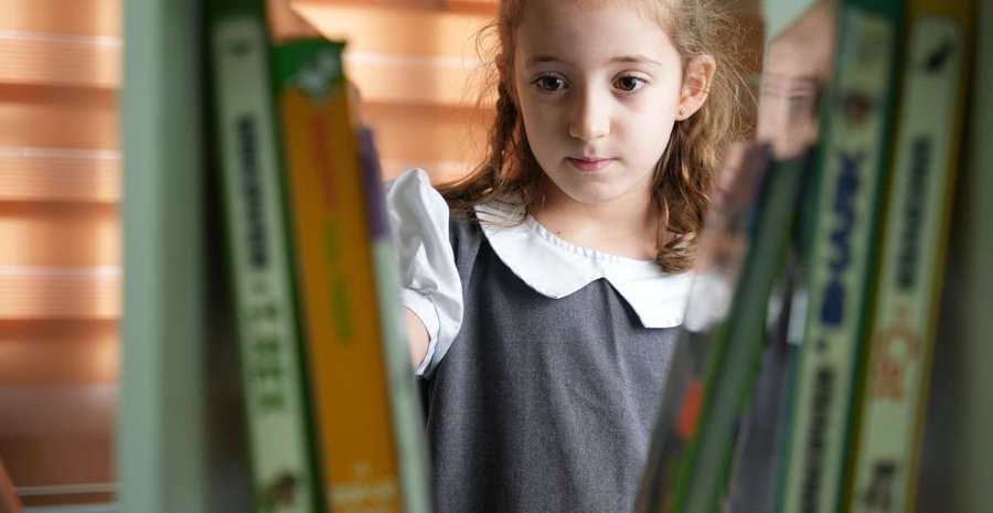 A student exploring the library at American Lyceum Muscat
